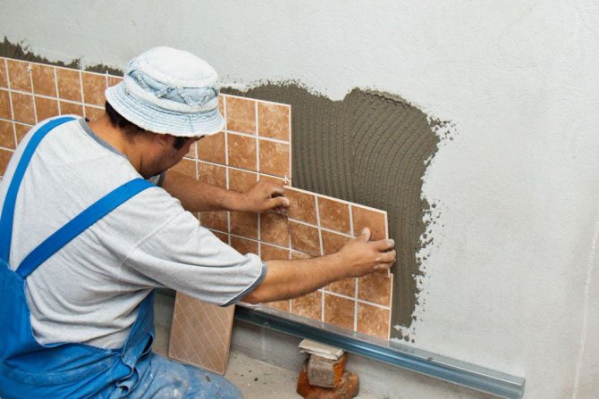 Le maître colle les carreaux au mur