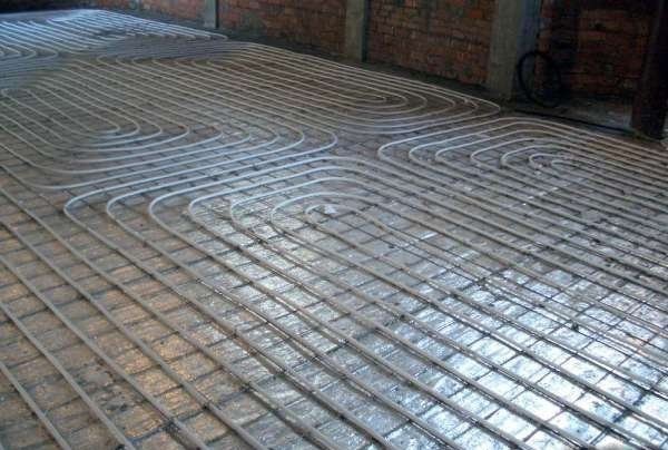 Sur la photo, il y a un treillis de renfort et des tuyaux posés pour le chauffage par le sol