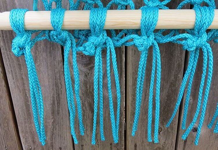 Nœuds de tissage d'une corde turquoise sur un bâton en bois