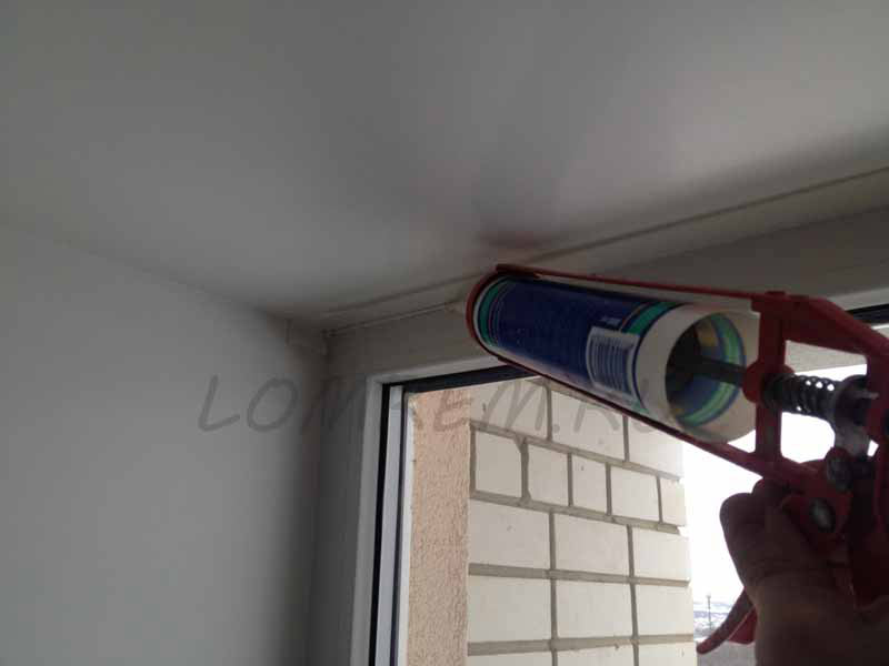 Nous pressons le mastic acrylique, remplissant la jonction de la fenêtre avec une pente